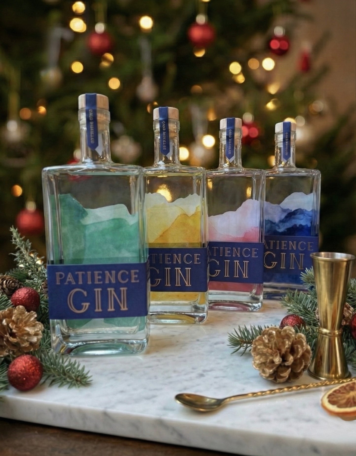 Four bottles of Patience Gin on a marble surface with a Christmas tree in the background.