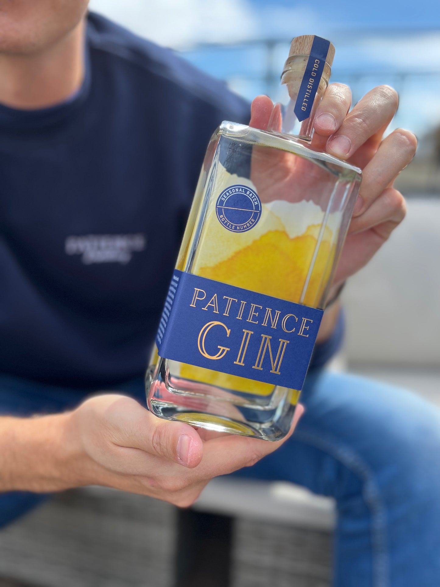 Person holding a bottle of Patience Summer Gin with a blurred background