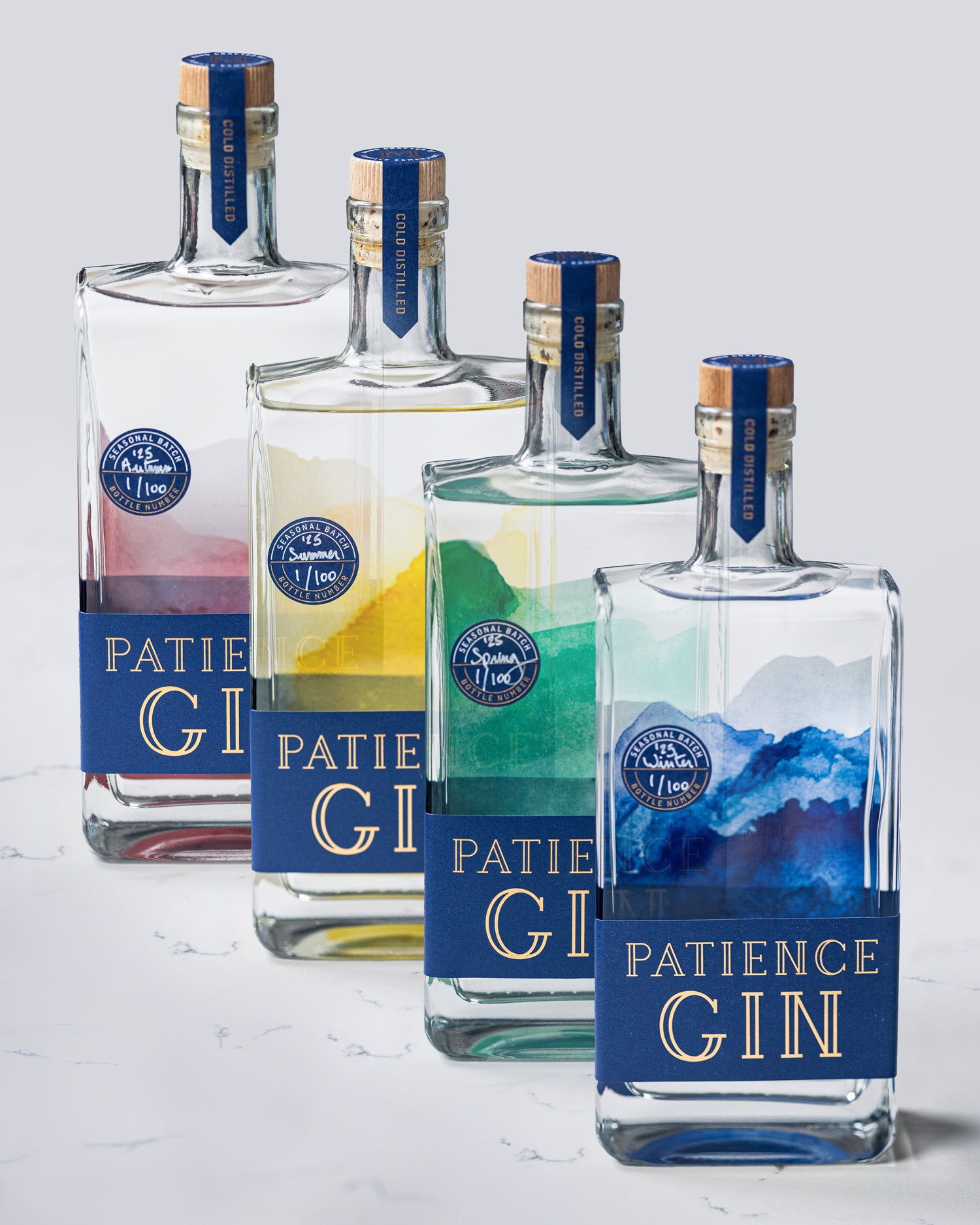 Four bottles of Patience Gin with colorful labels on a light background
